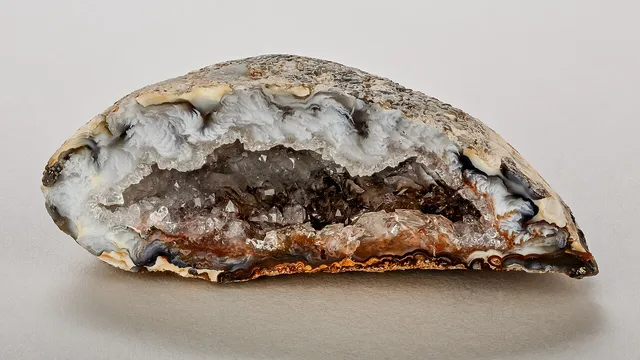 Una geoda partida por la mitad: por fuera parece un pedrusco cualquiera, y por dentro el hueco está tapizado de cristales que han crecido hacia el centro.