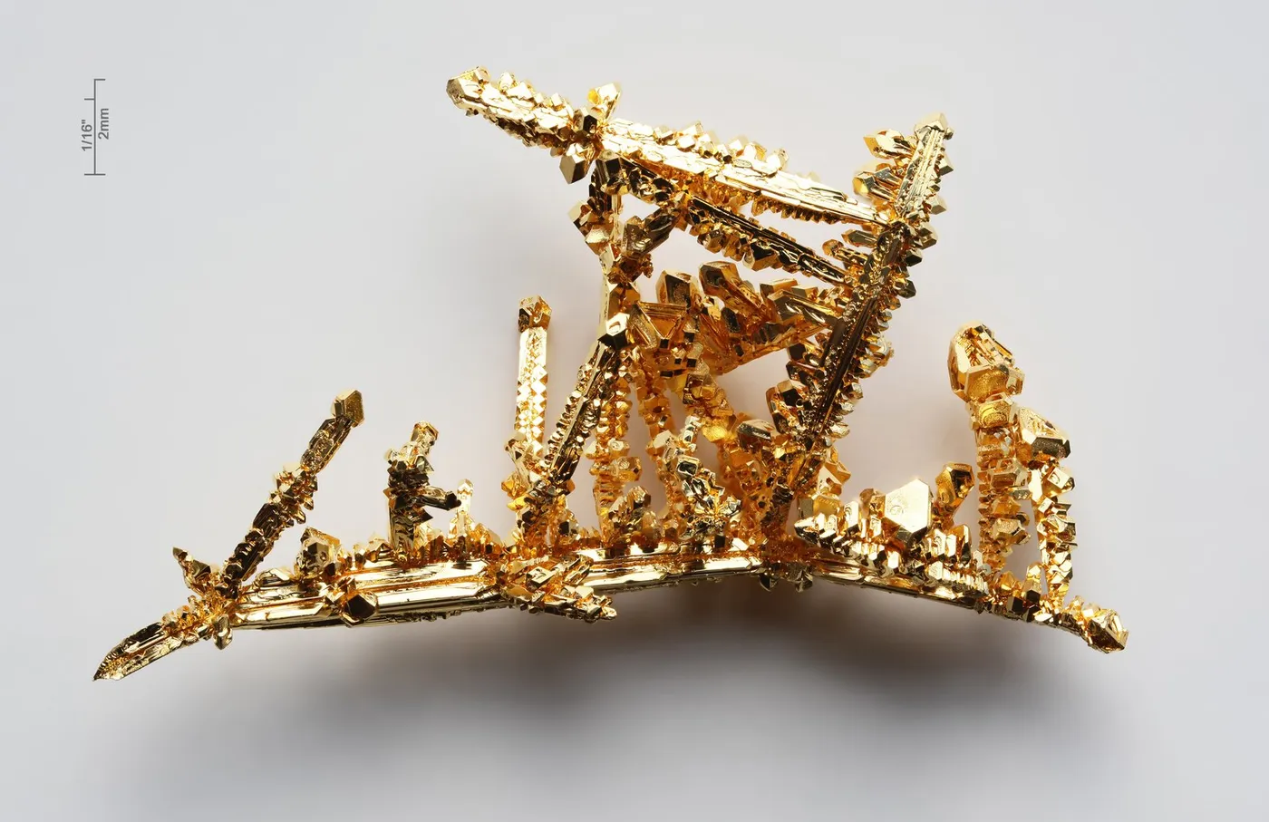 Oro puro cristalizado (la barrita de escala mide 2 mm). Dorado por sí mismo: se queda parte del azul de la luz y devuelve el resto.
